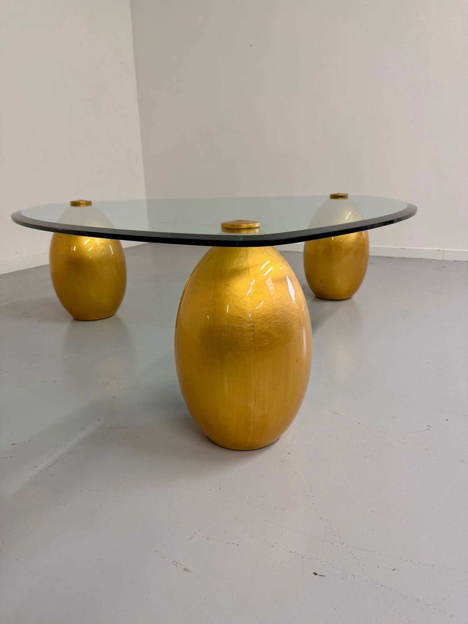Vintage Italian design coffee table with a glass top and gold base, dating from the 1980s.