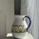 Large white terracotta carafe with a stylized green and yellow frieze pattern