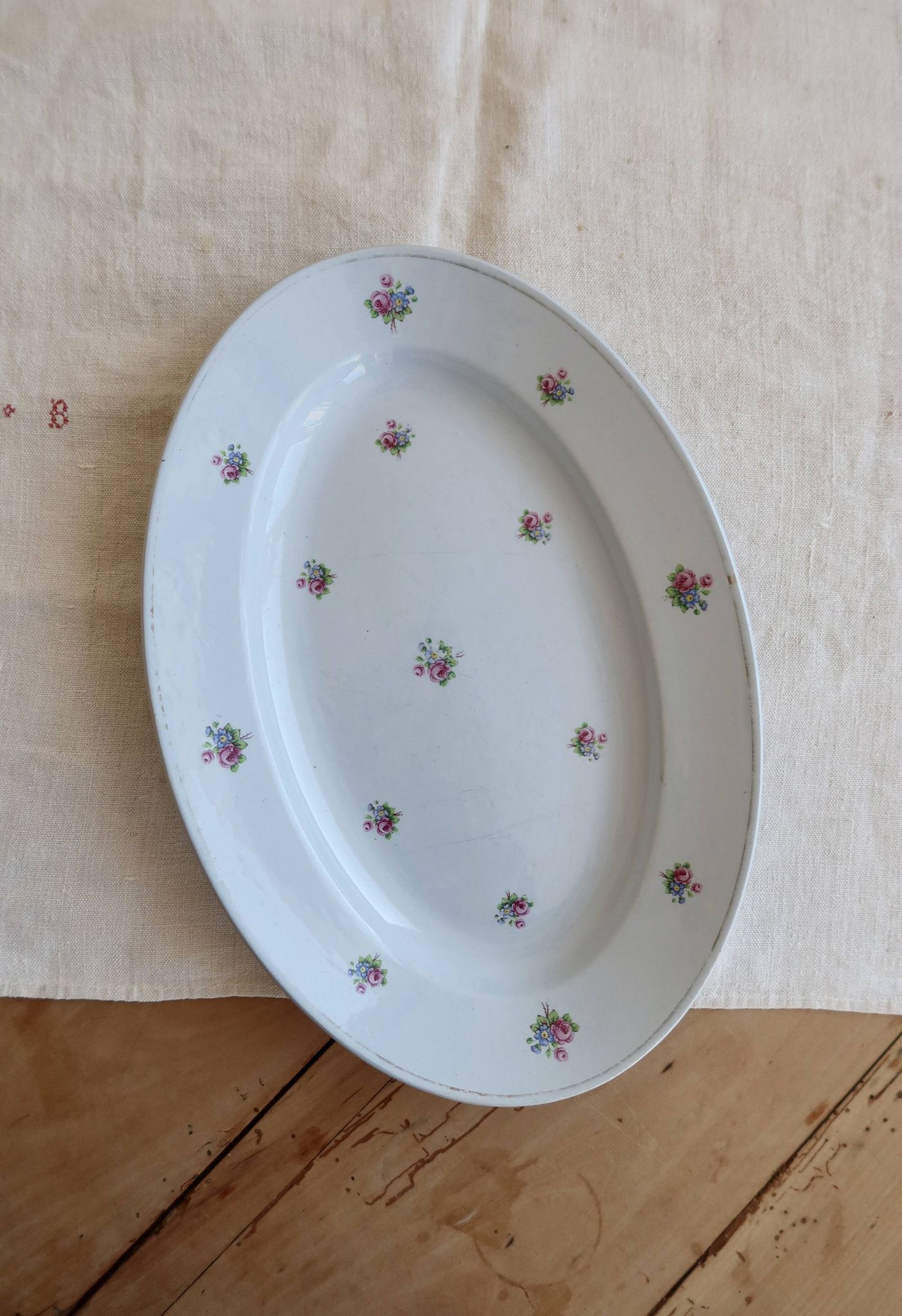 Antique oval serving dish in pale blue earthenware with a small flower design.