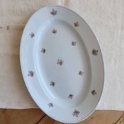 Antique oval serving dish in pale blue earthenware with a small flower design.