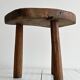 Antique three-legged stool made of raw solid wood.