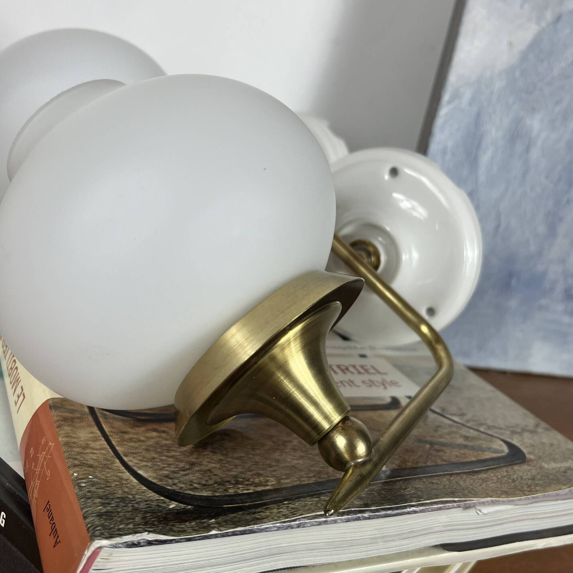 Pair of vintage wall sconces in brass with white glass globe shades.