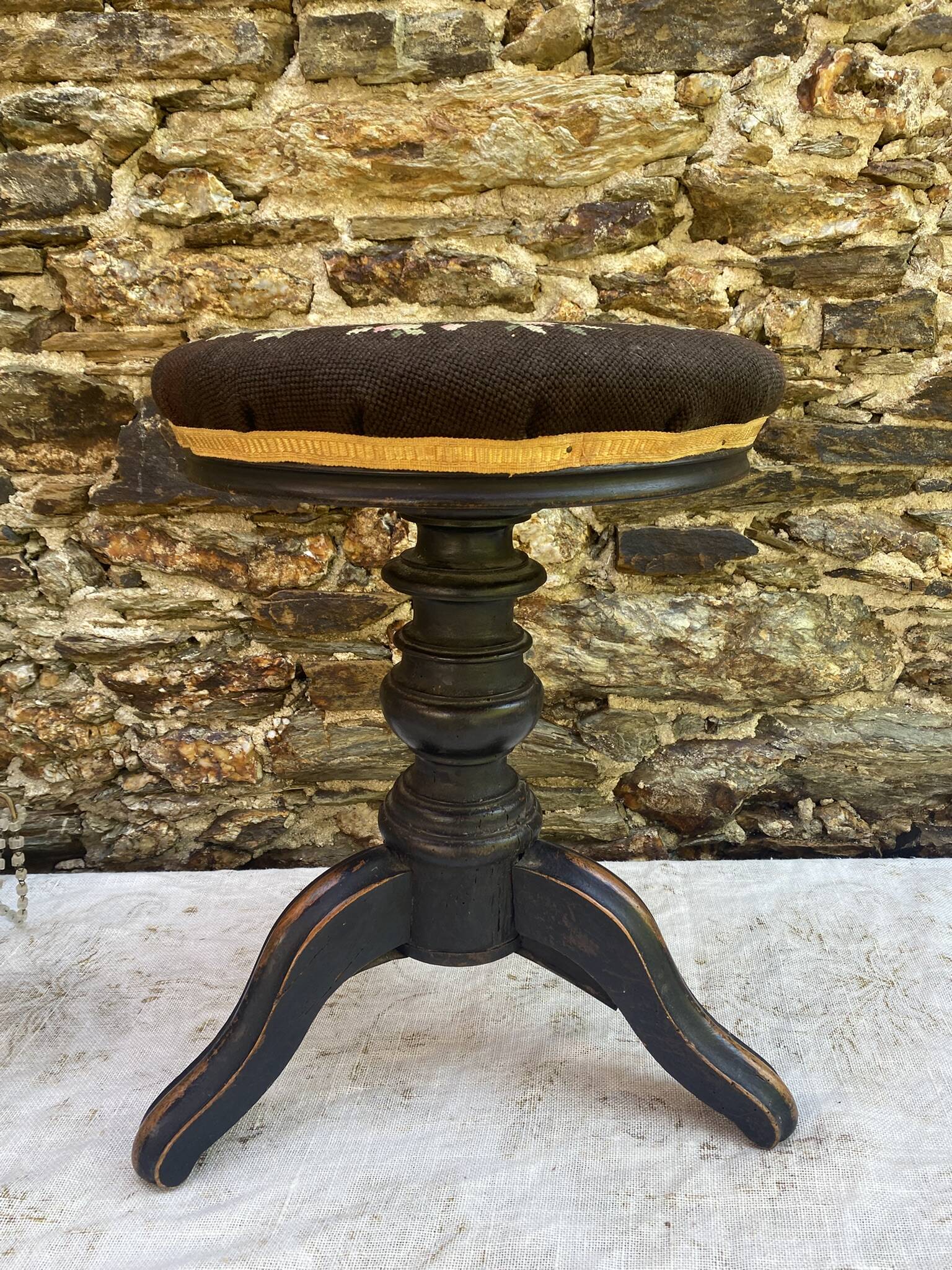 Old adjustable piano stool, blackened wood, metal screws, embroidered seat.