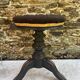 Old adjustable piano stool, blackened wood, metal screws, embroidered seat.