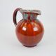 Large red and blue glazed ceramic pitcher signed Delène under the base