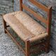 Wooden-backed bench with straw seat, 1970s.