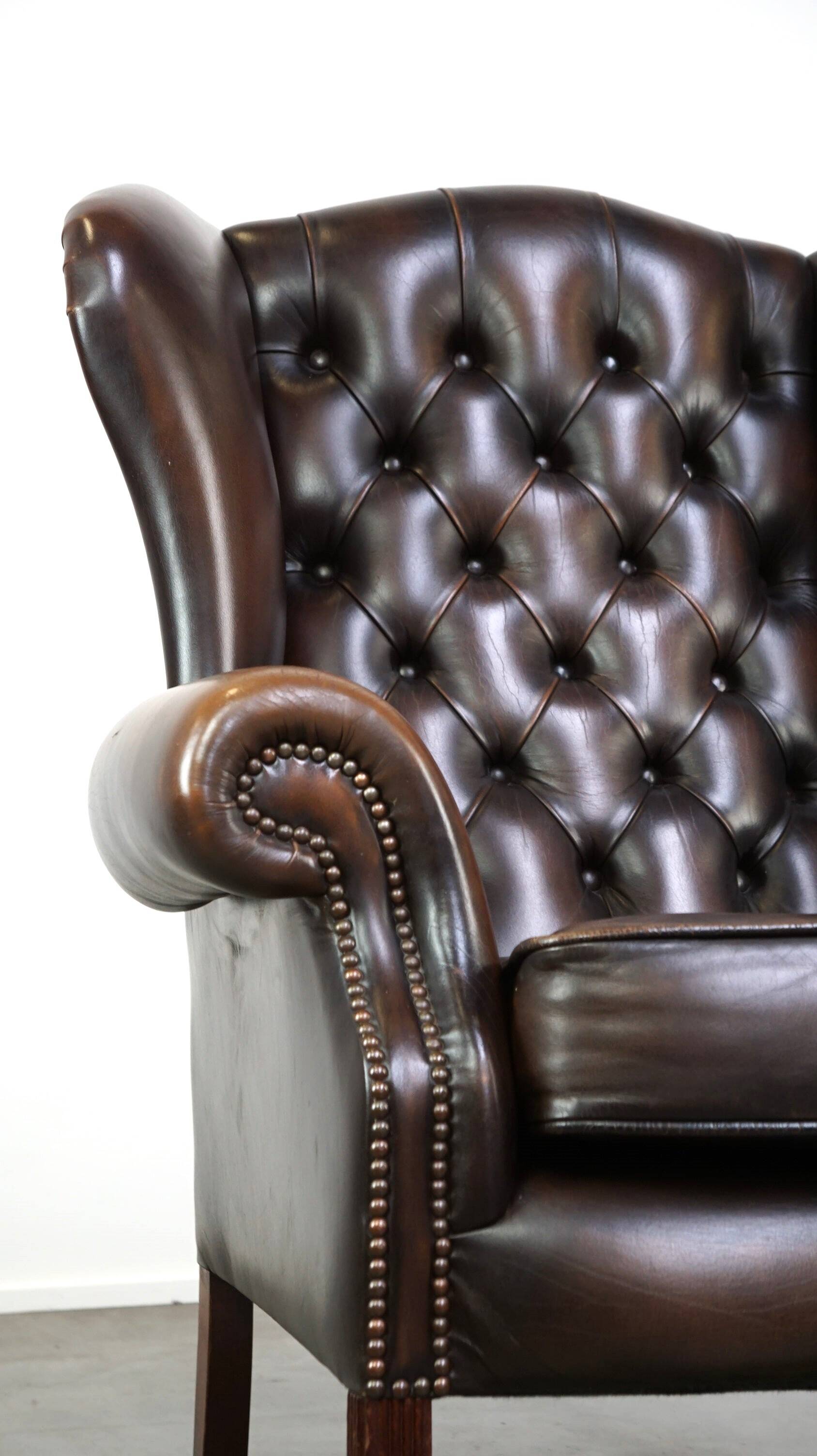 Chesterfield wing chair in dark brown leather with a luxurious appearance
