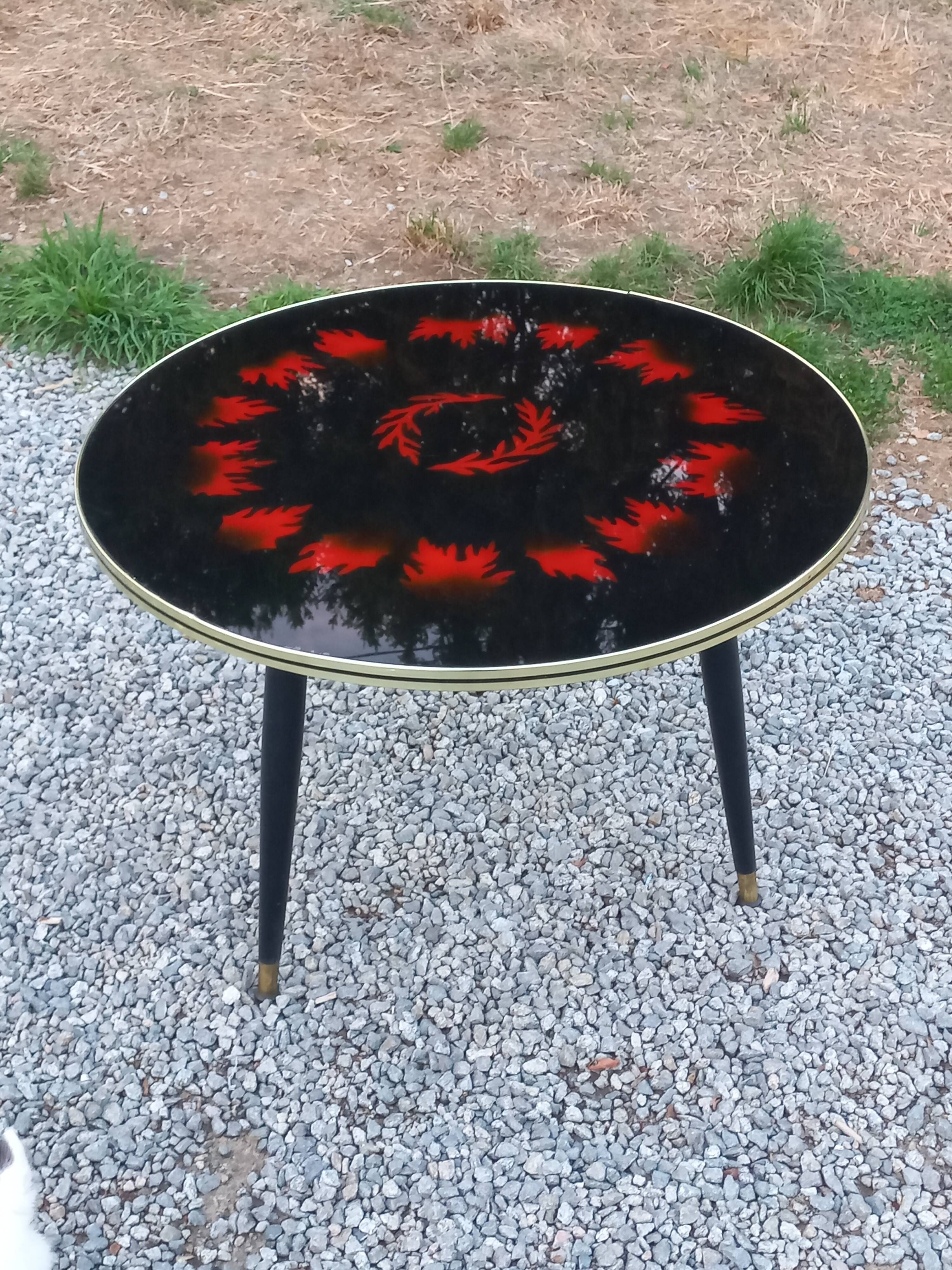 Vintage coffee table with glass top and tripod legs in blackened wood from the 1960s.