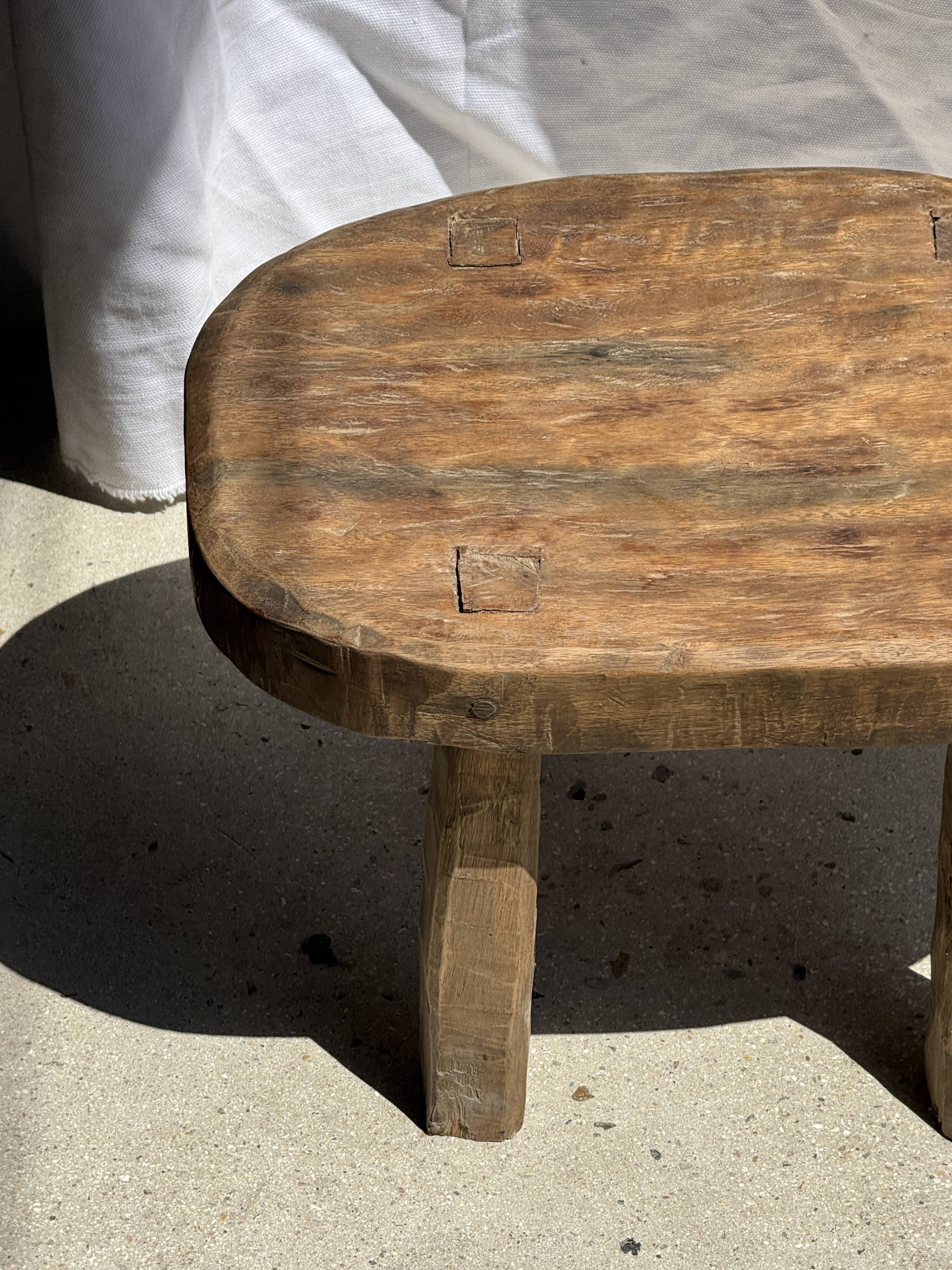 Small stool, oval solid teak side table with curved legs in wabi-sabi style.