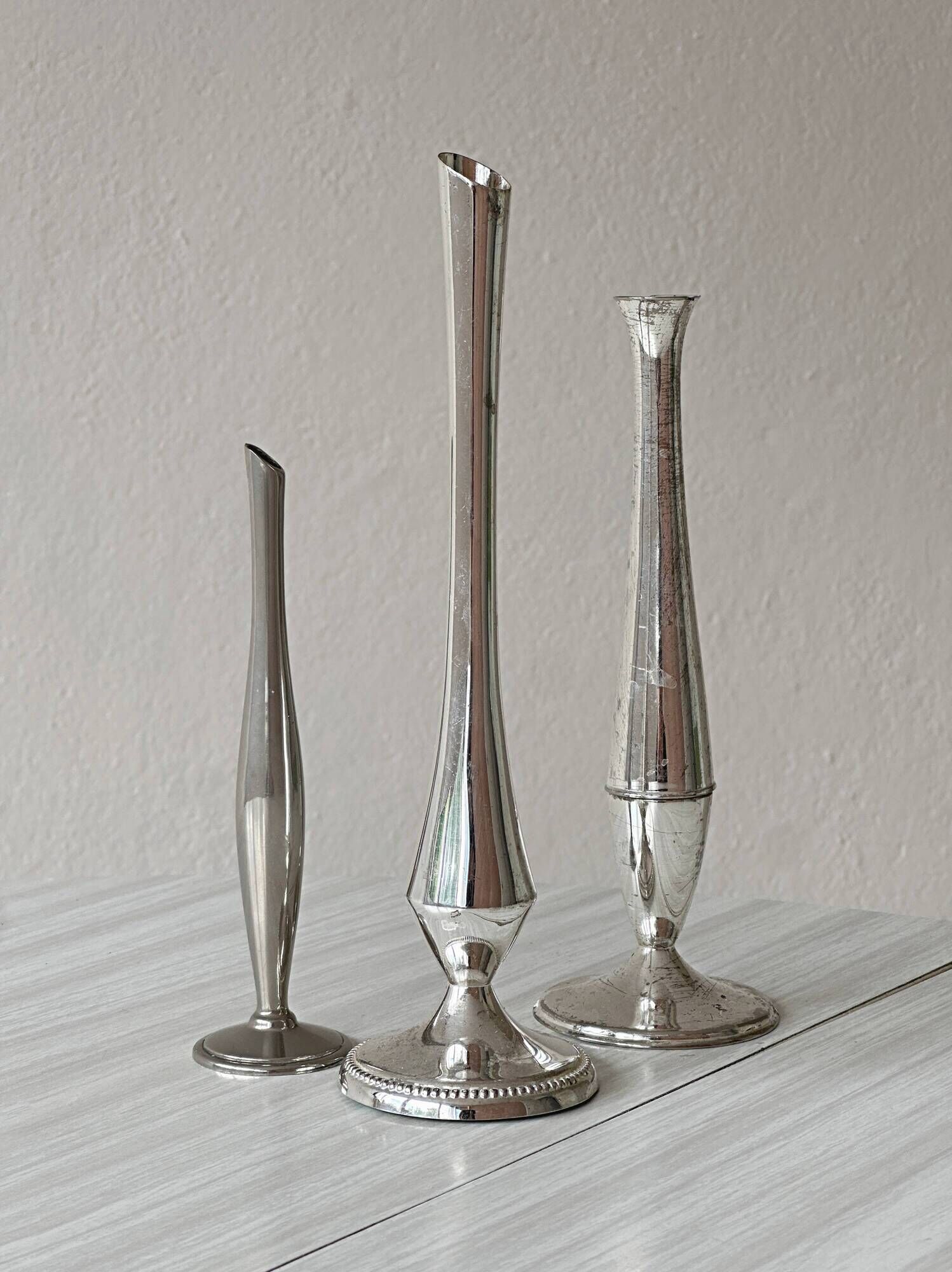 Set of three lightweight silver-coloured metal vases.