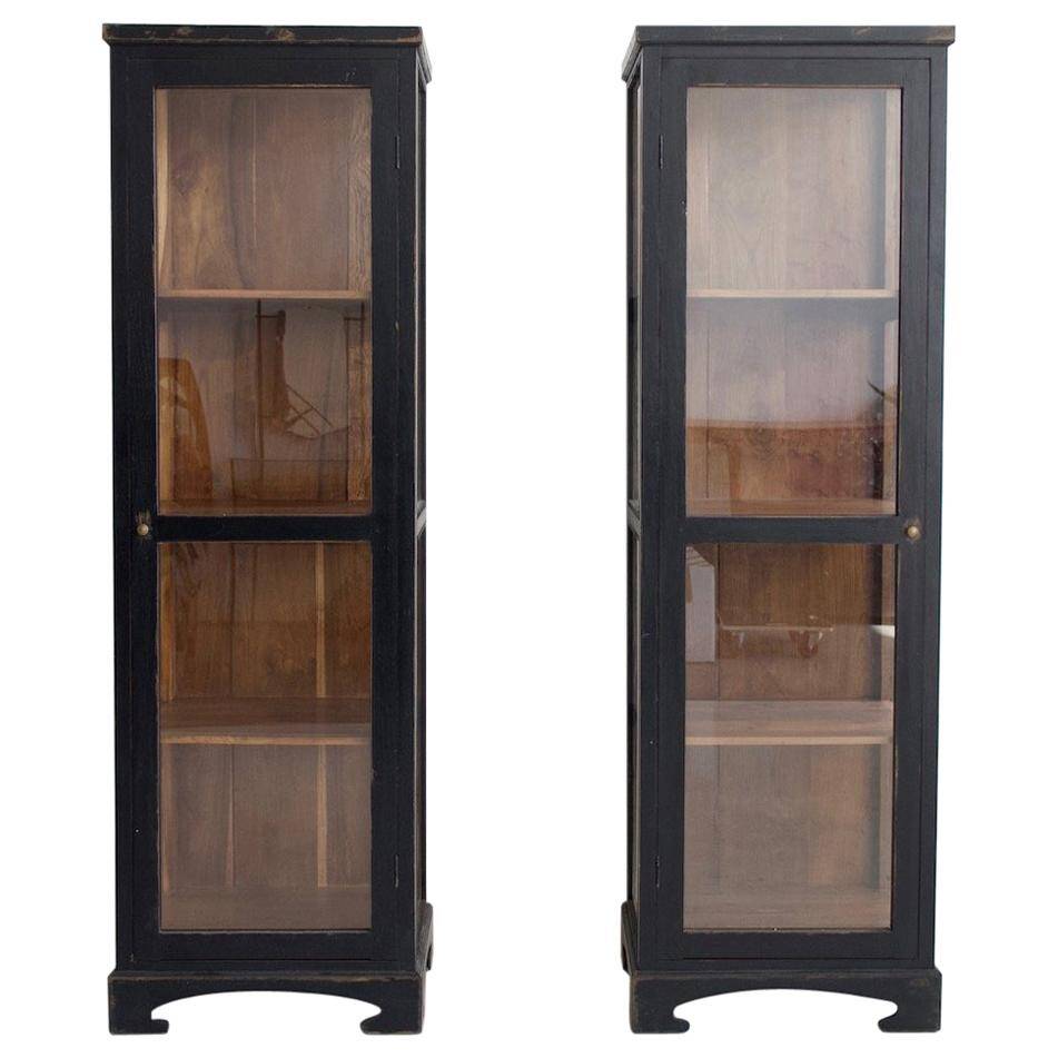 Pair of black wooden display cabinets with glass doors.