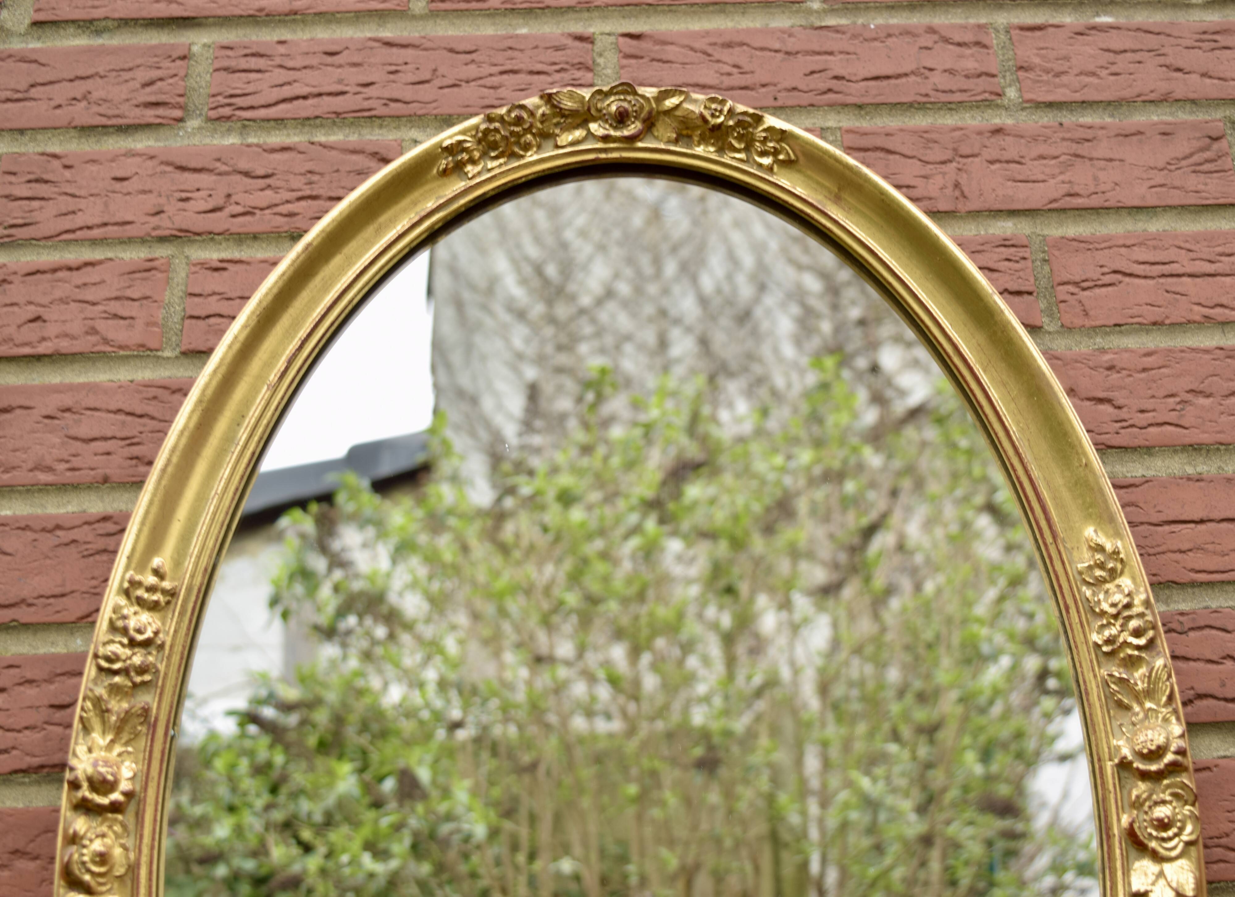 Old large oval wall mirror in golden resin