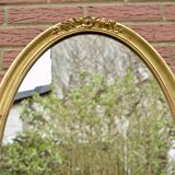 Old large oval wall mirror in golden resin