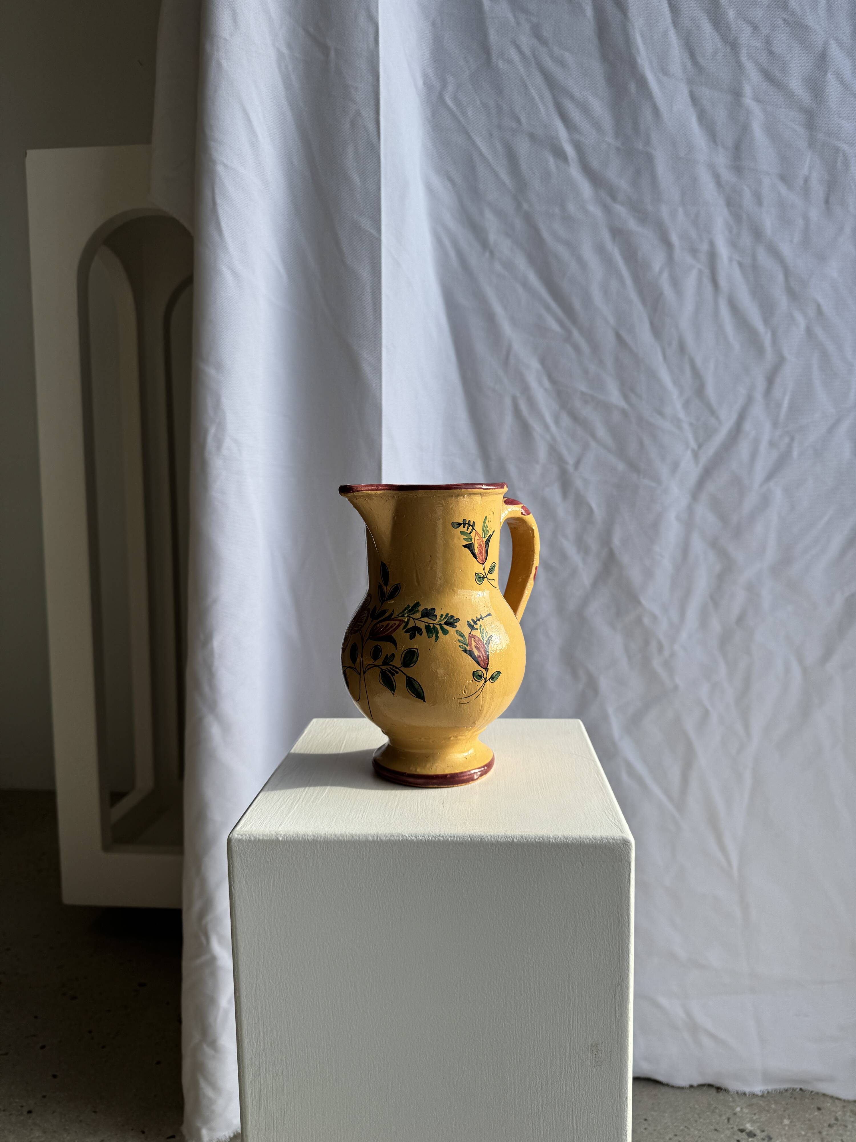 Large antique handmade ochre yellow jug with a pink flower pattern.