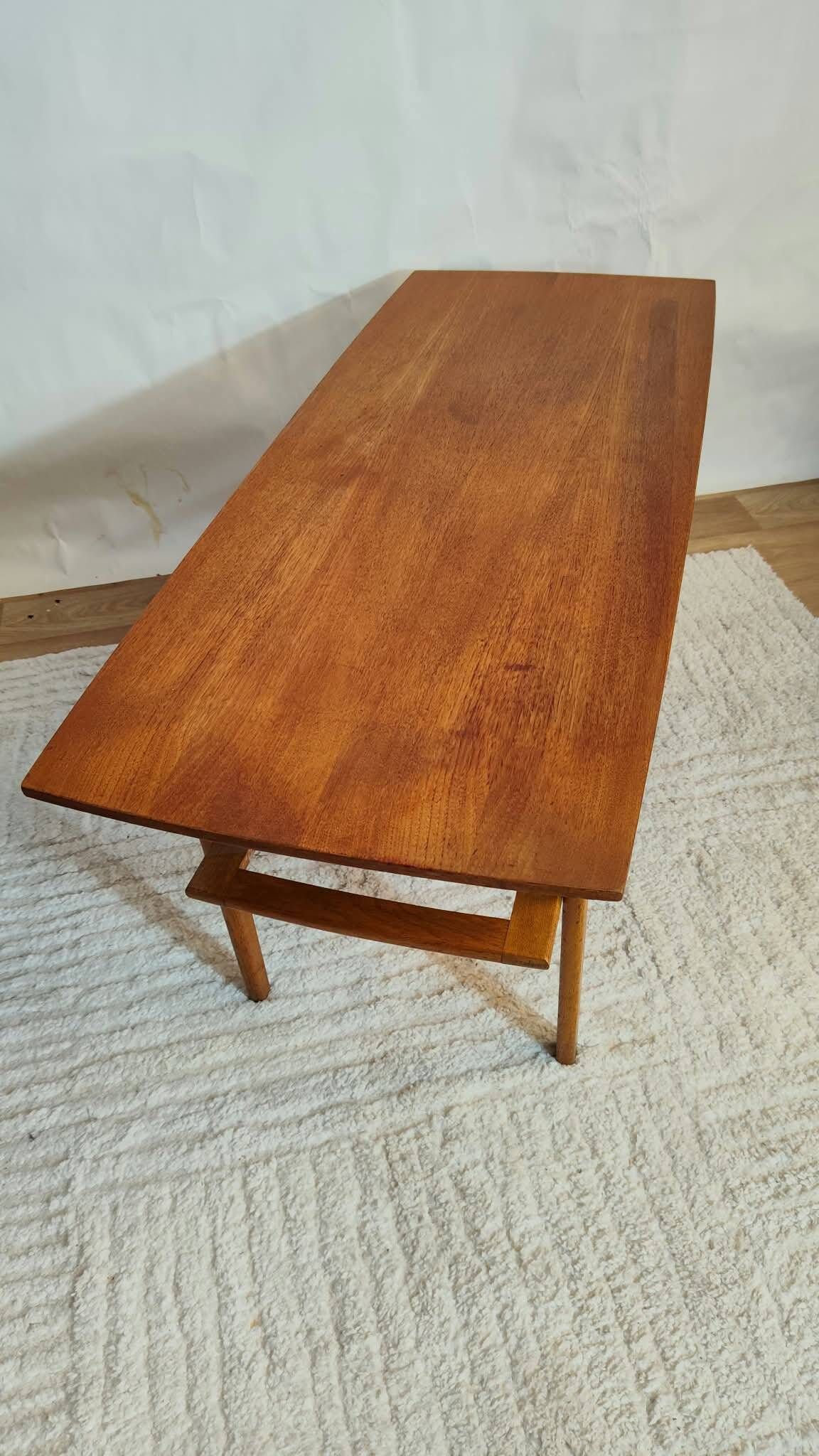 Scandinavian coffee table in teak with a lower shelf and brass bars.
