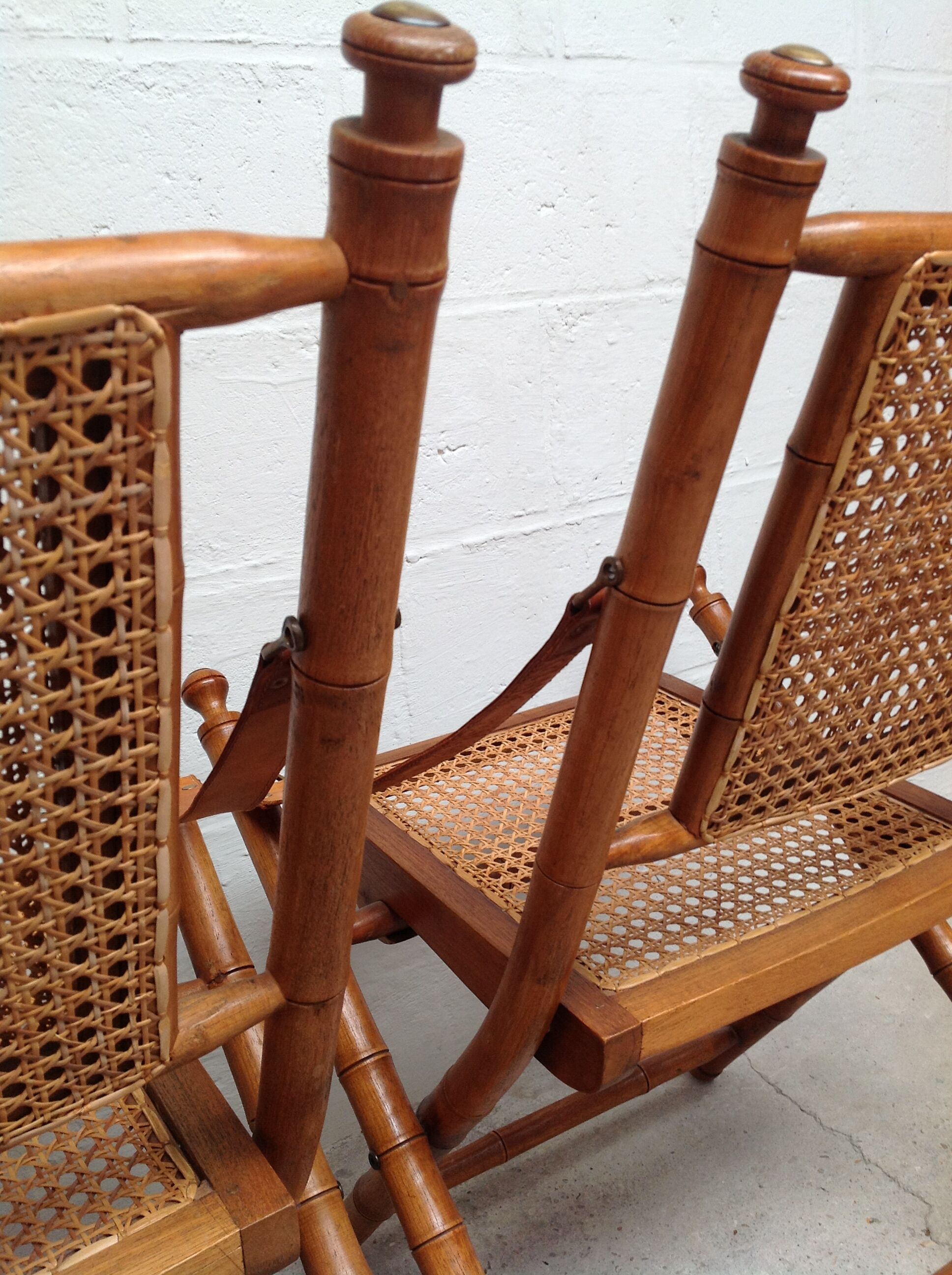 Pair of folding chairs in bamboo and caning, leather and brass