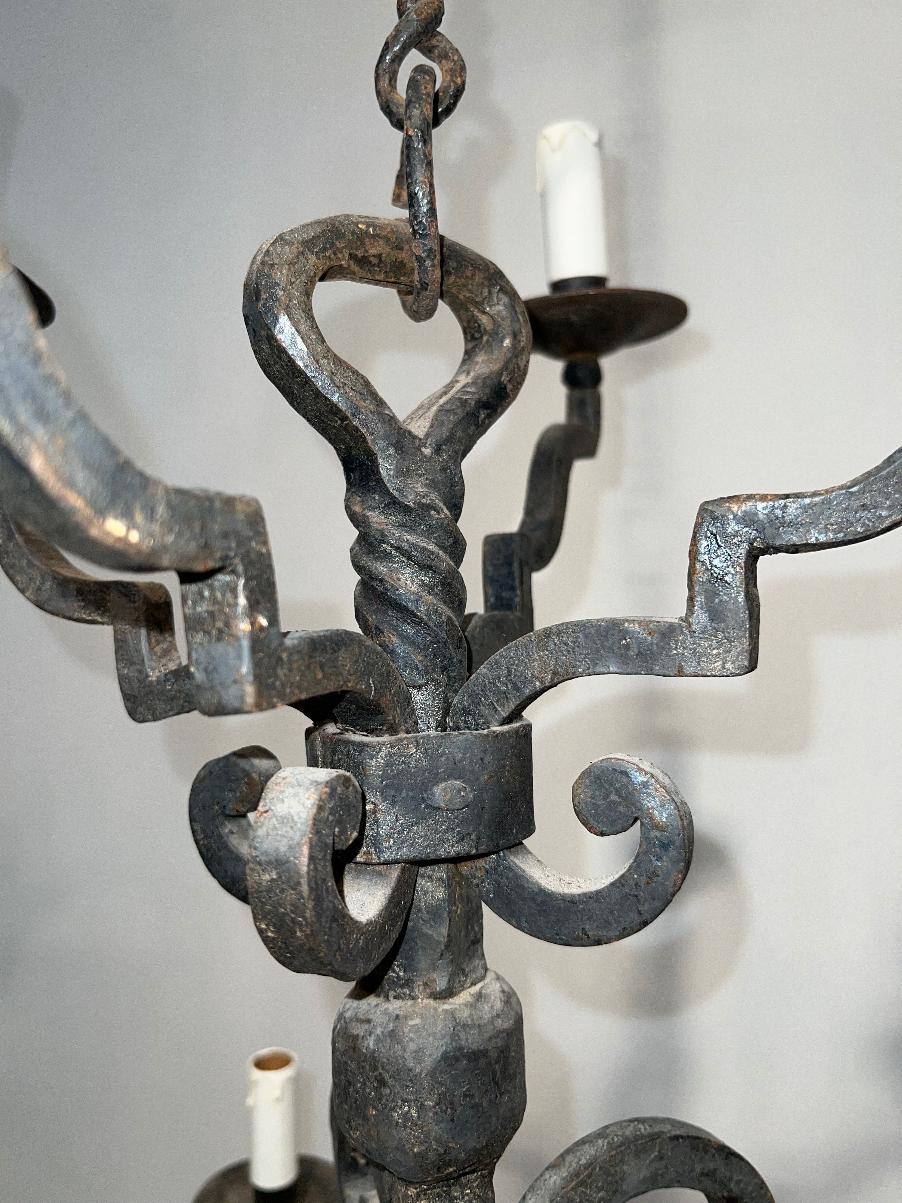 Two-tiered wrought iron chandelier with eight light arms in Gothic style.