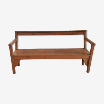 Church bench in fir tree with armrests