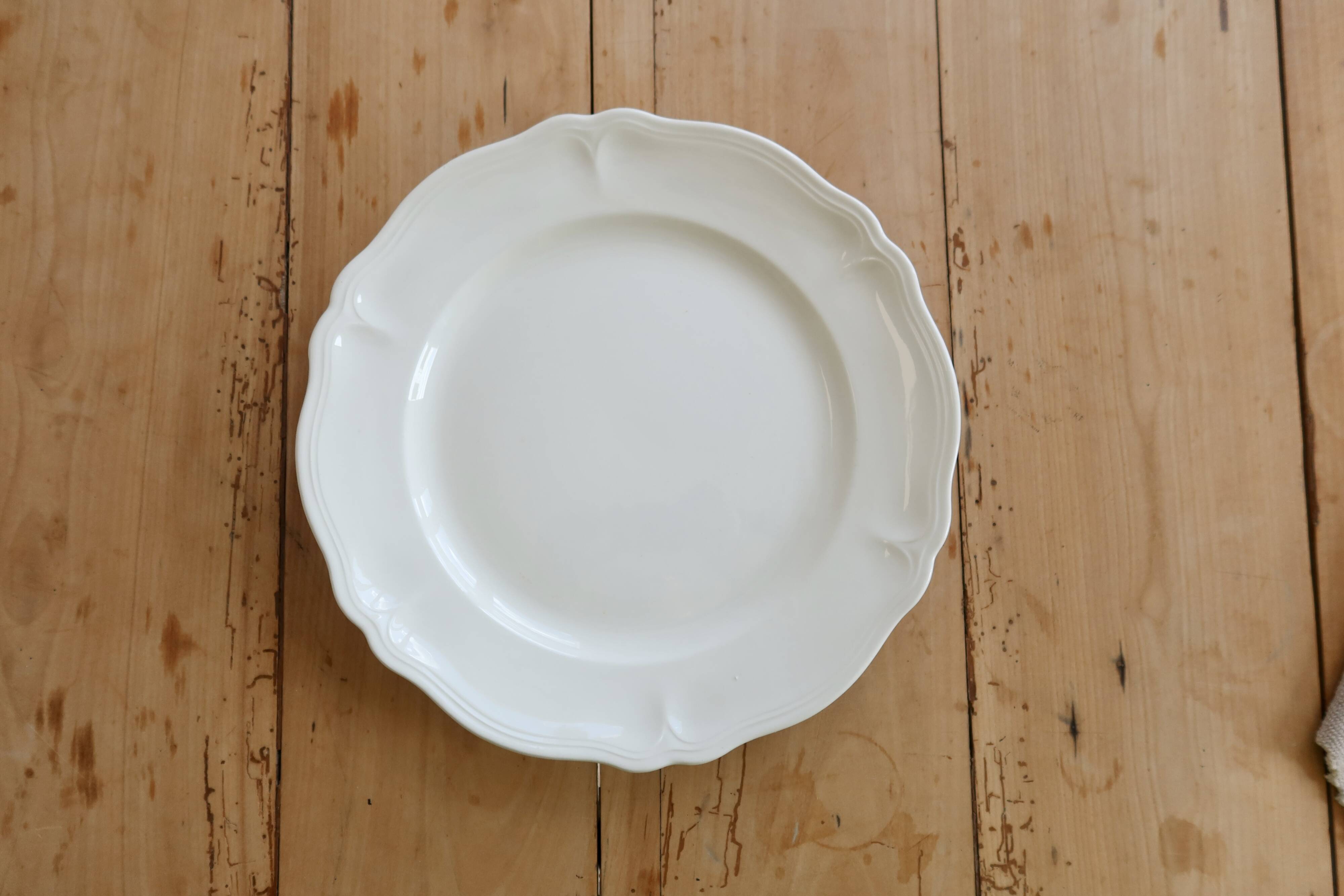 Round vintage ivory earthenware serving dish with scalloped rim.