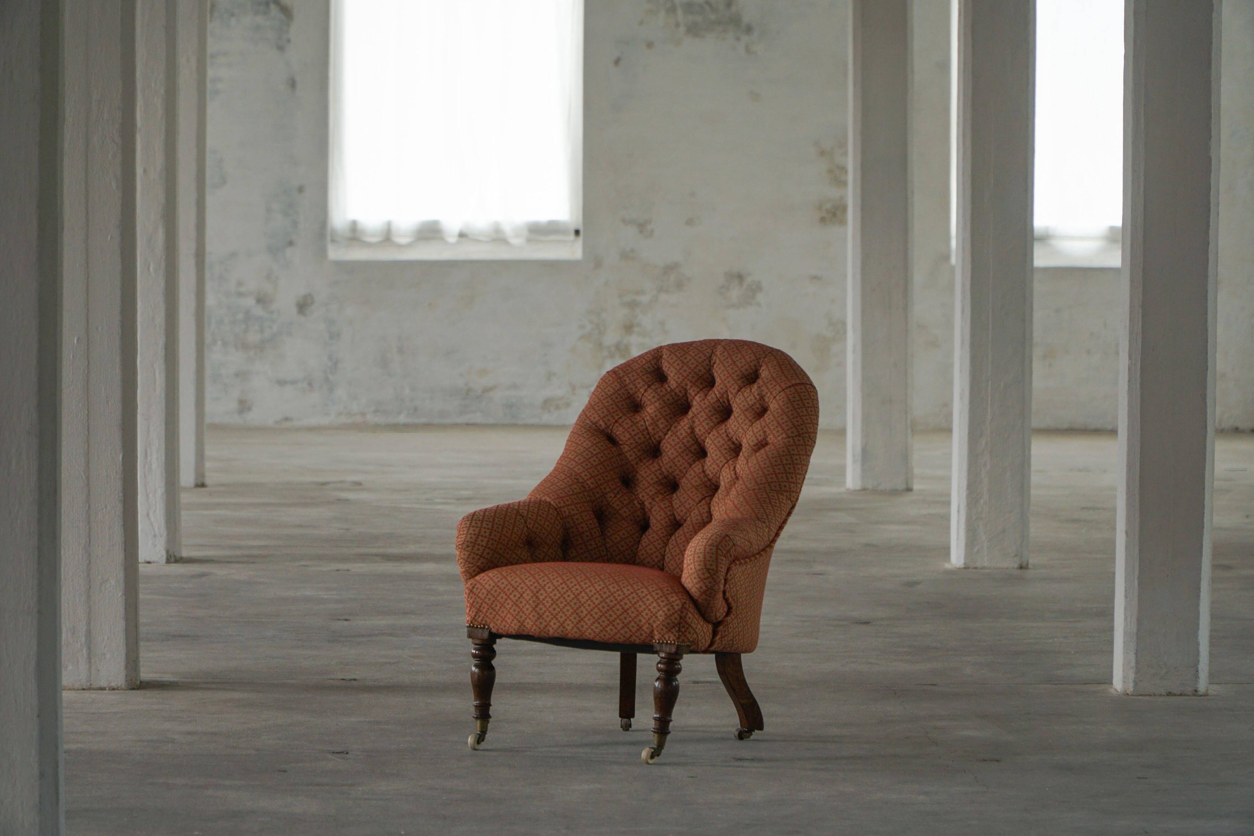 Victorian mahogany armchair, with wheels and coloured fabric, England, early 1900s.