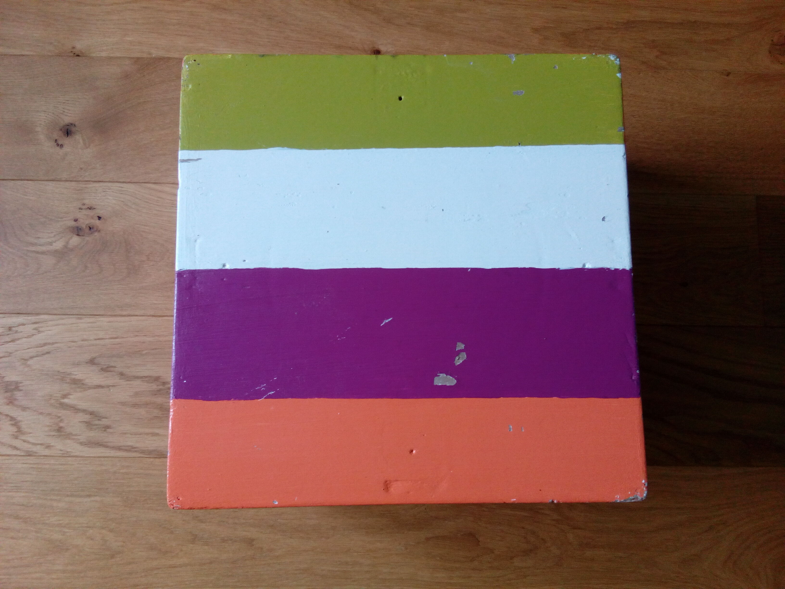 Low wooden stool painted in bright colours
