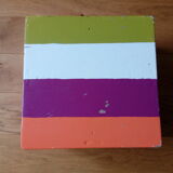 Low wooden stool painted in bright colours