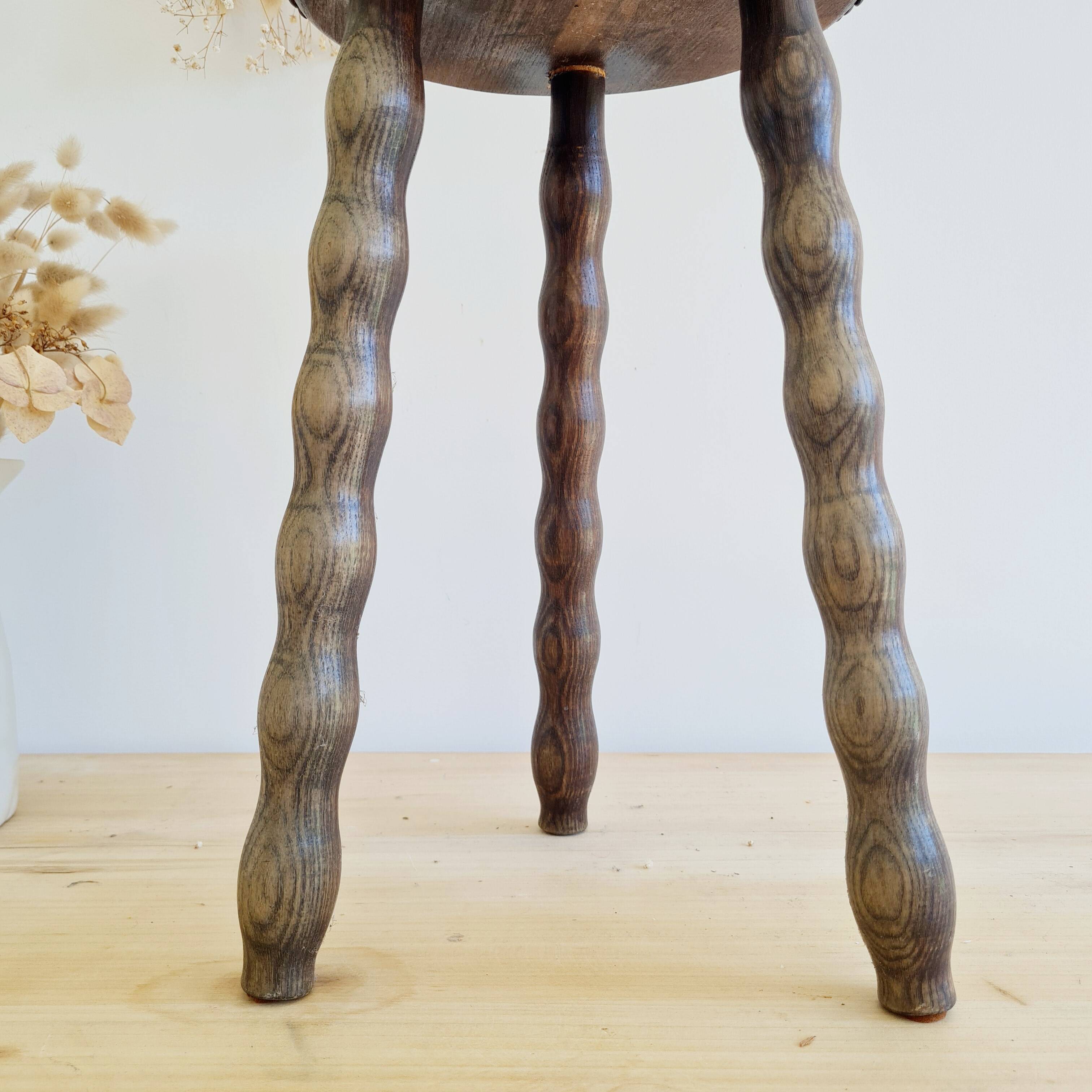 Antique tripod stool with turned wooden legs and leather seat.