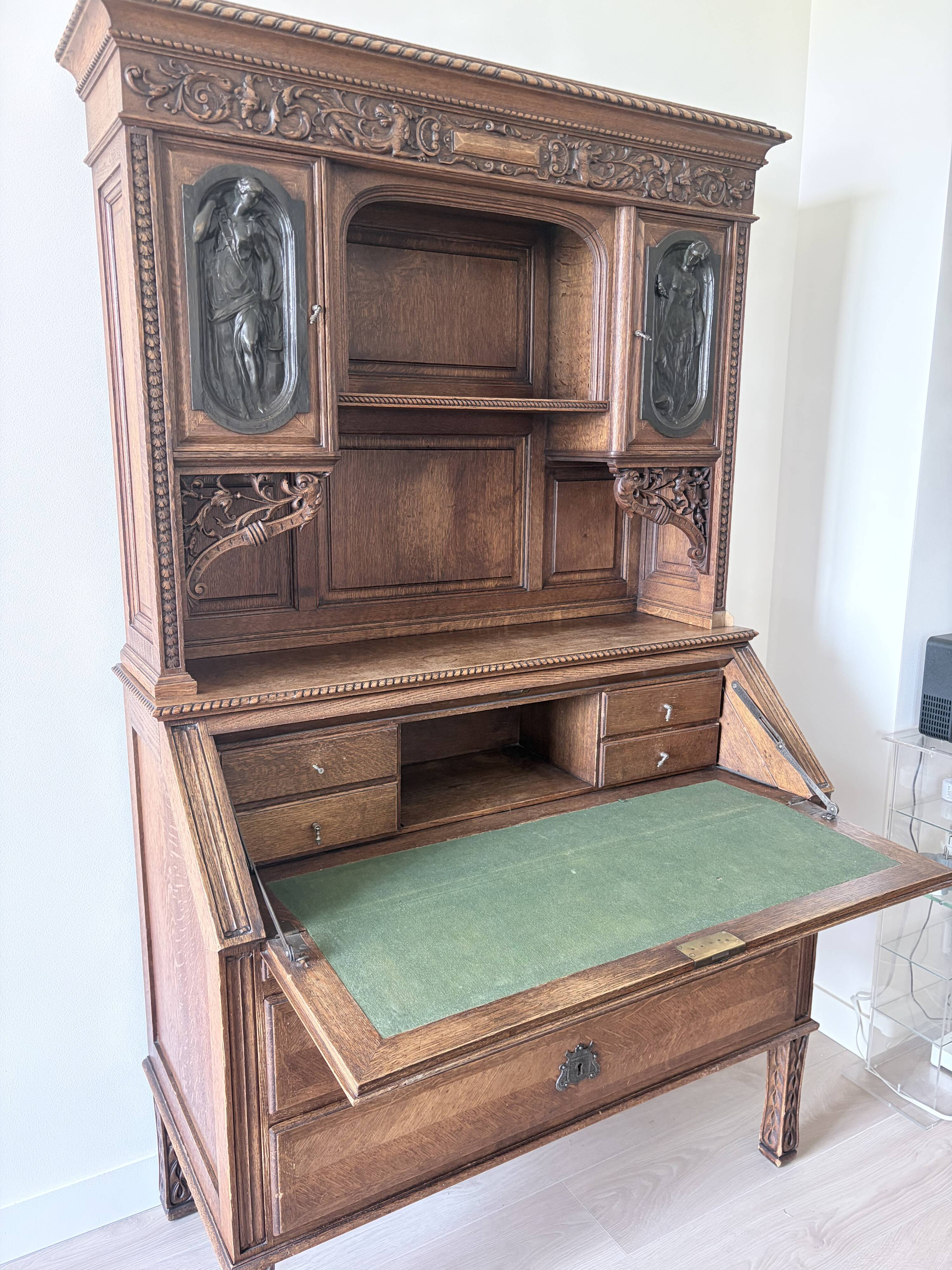 Large secretary with a drop-down front in carved oak, neo-Renaissance style.
