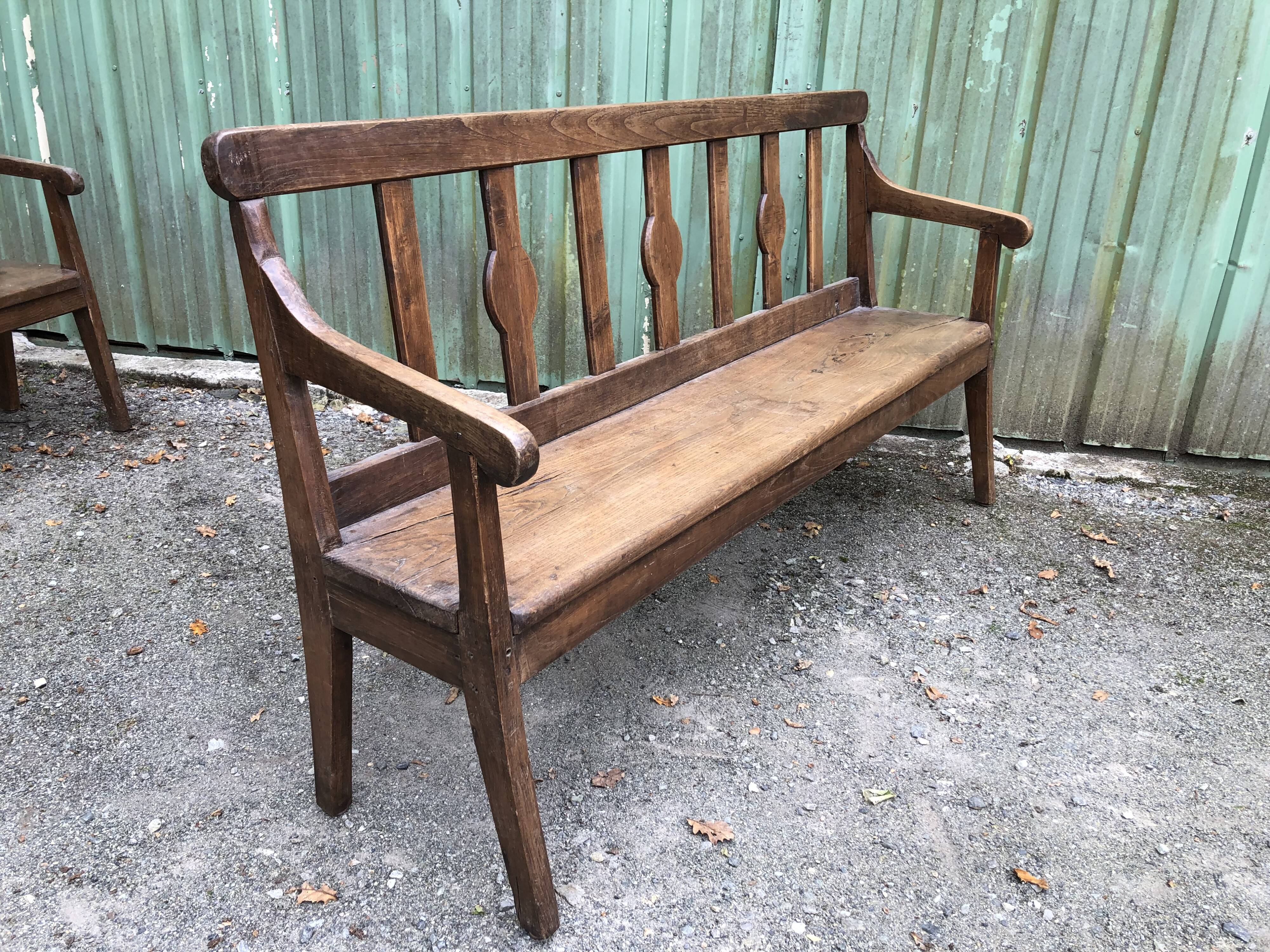 Duo of old solid oak benches with backs and armrests.