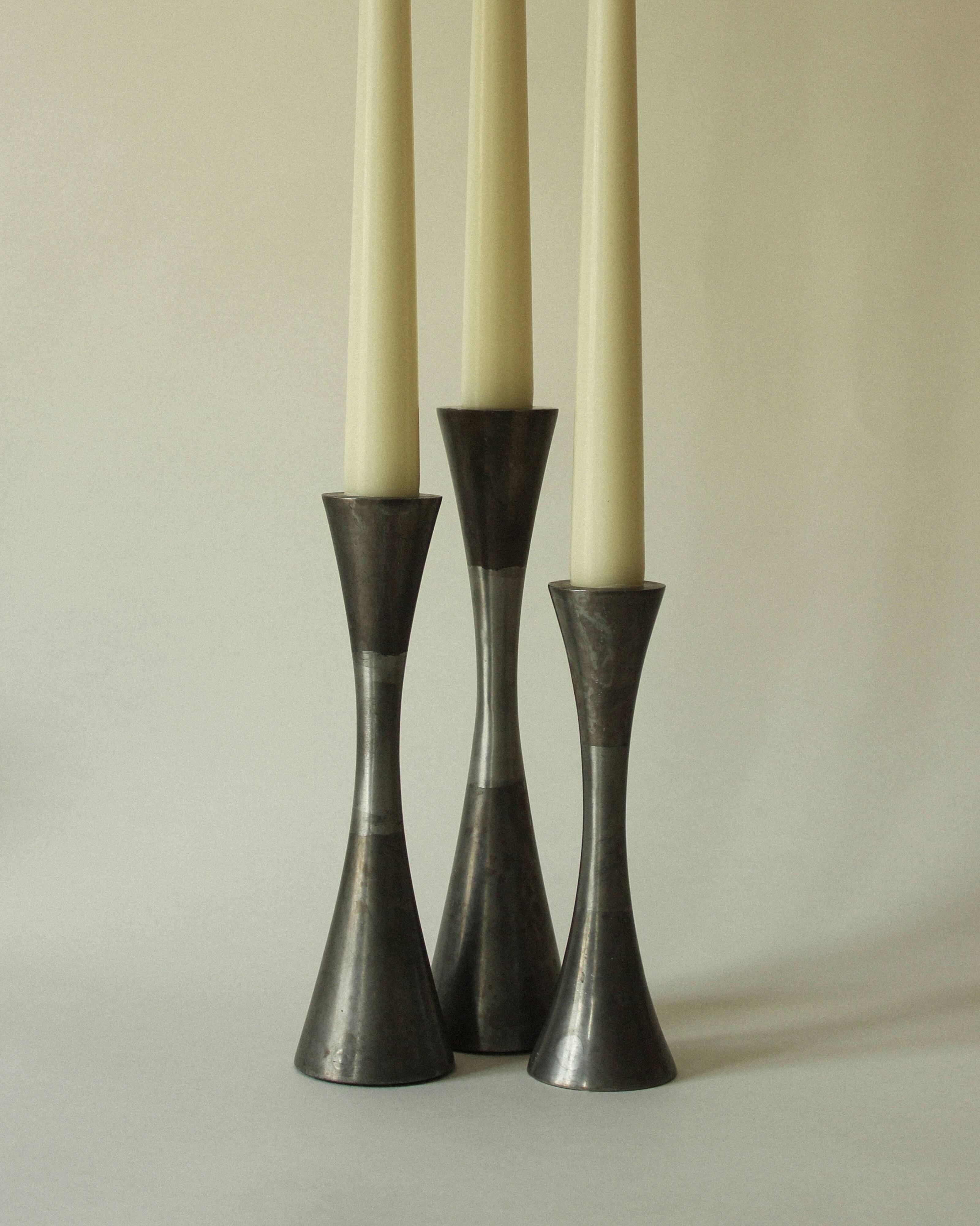 Set of three diabolo-shaped candle holders made of cast steel.