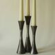 Set of three diabolo-shaped candle holders made of cast steel.