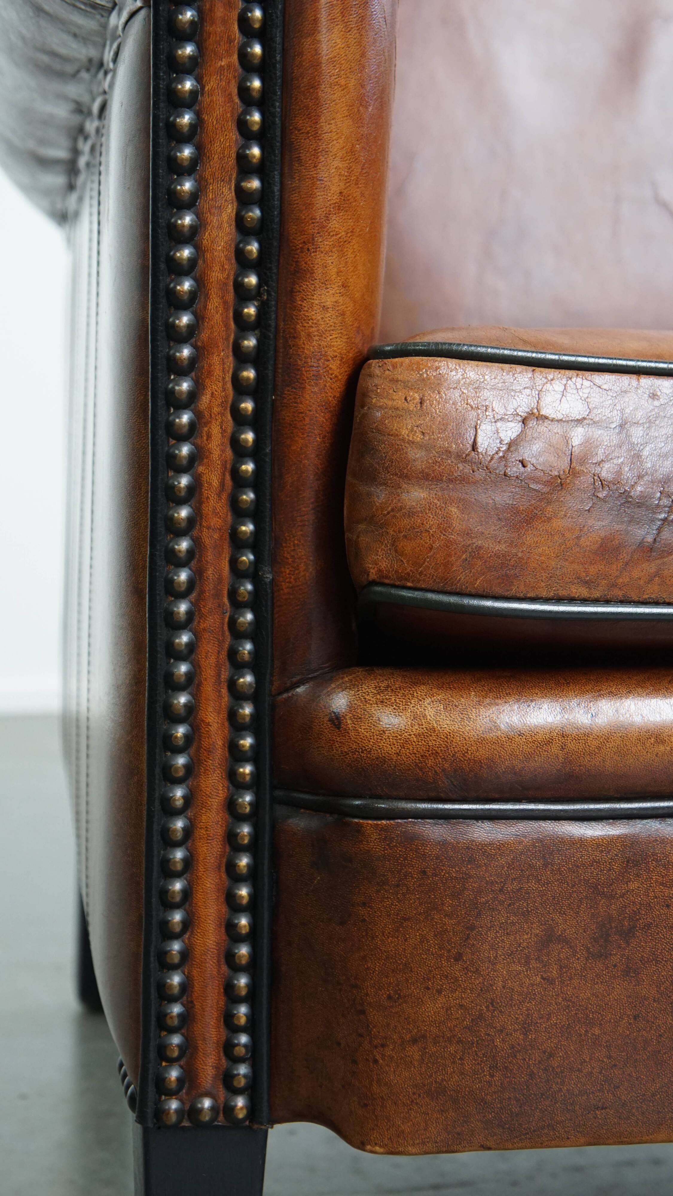 Sheepskin leather armchair in a cognac color with black piping