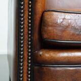 Sheepskin leather armchair in a cognac color with black piping
