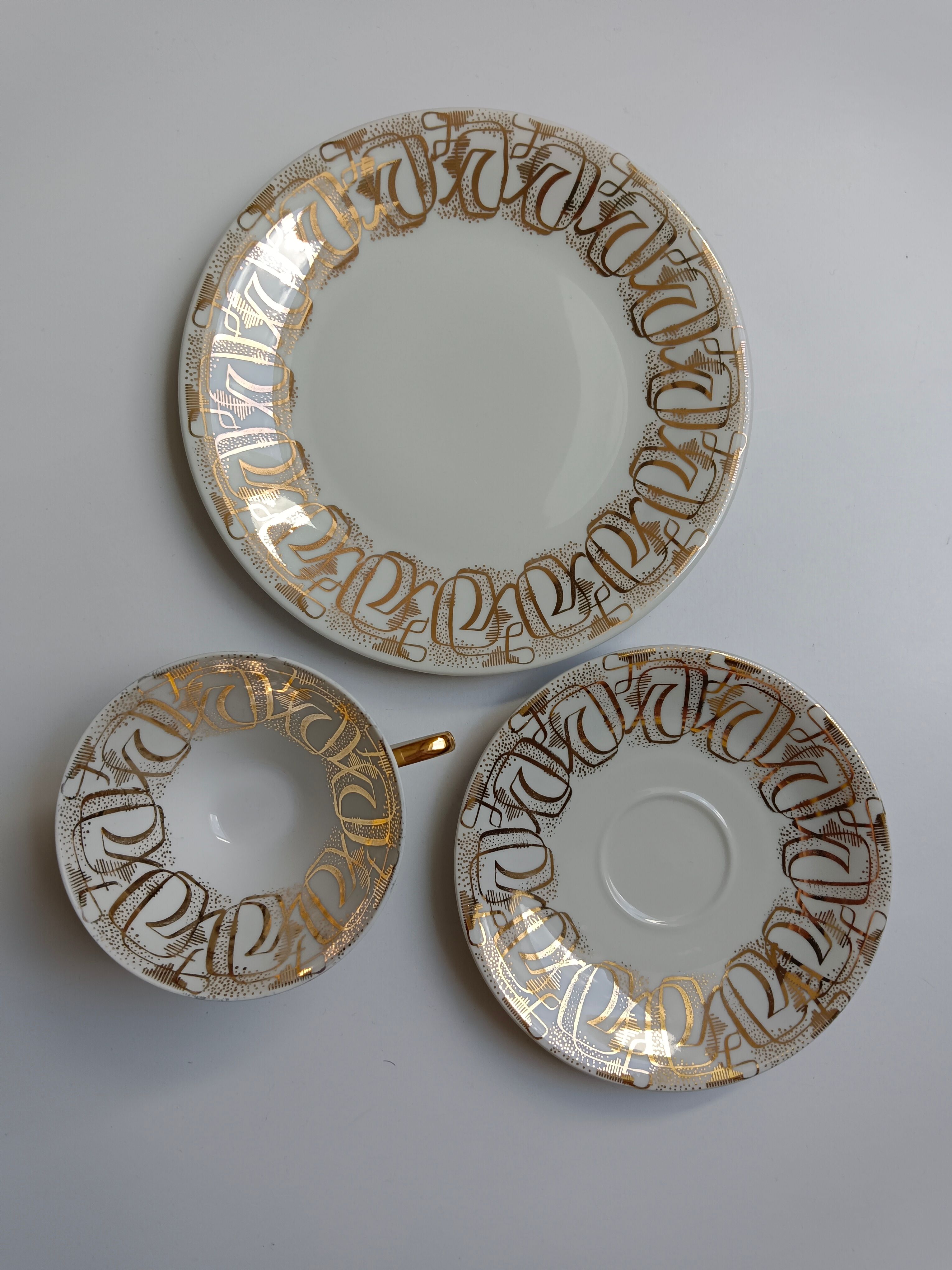 Solitaire tea cup, saucer, and dessert plate in white and gold.