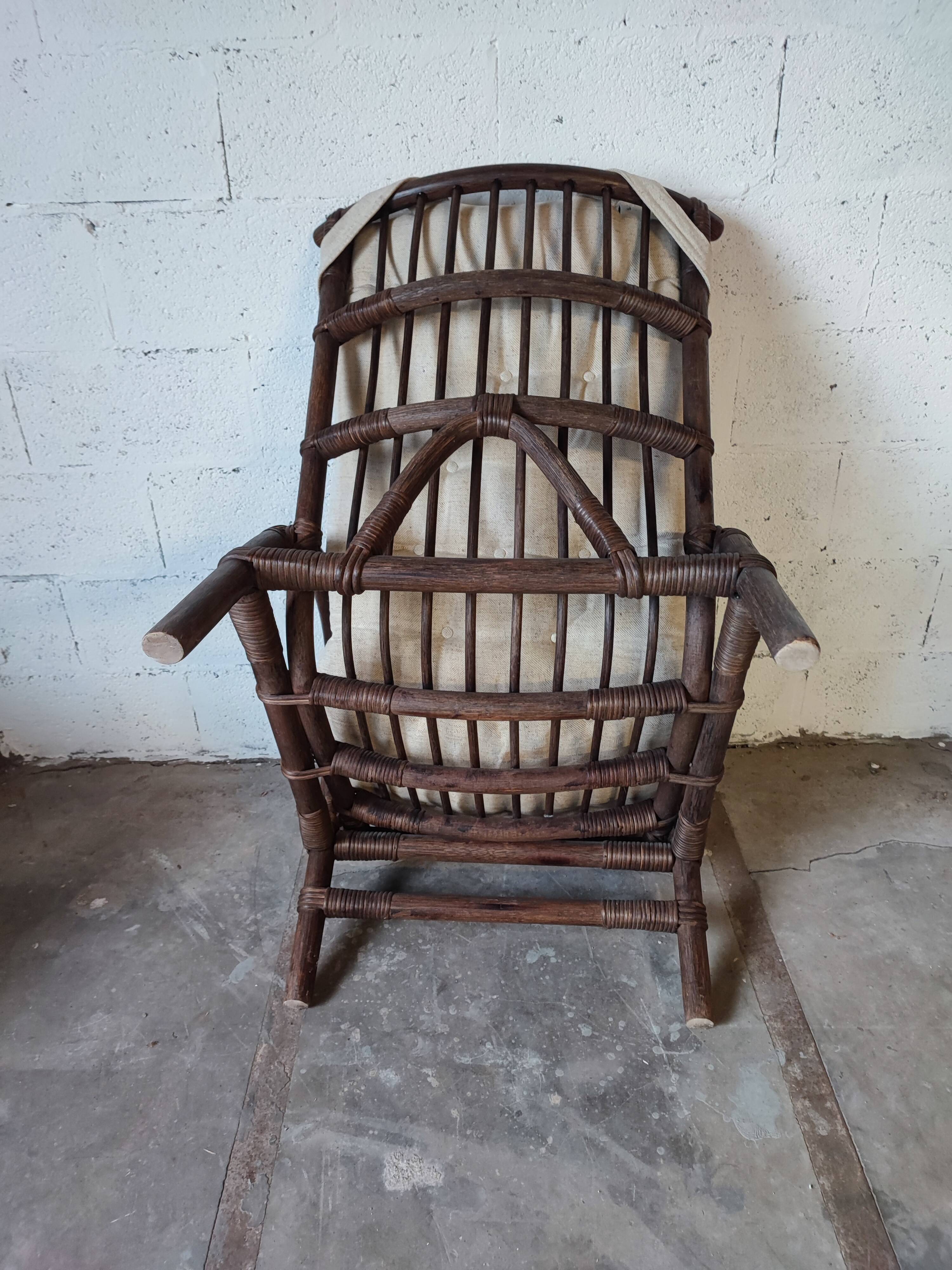 Relaxed armchair in bamboo and rattan with its small side table. Beige linen cushion.
