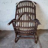 Relaxed armchair in bamboo and rattan with its small side table. Beige linen cushion.