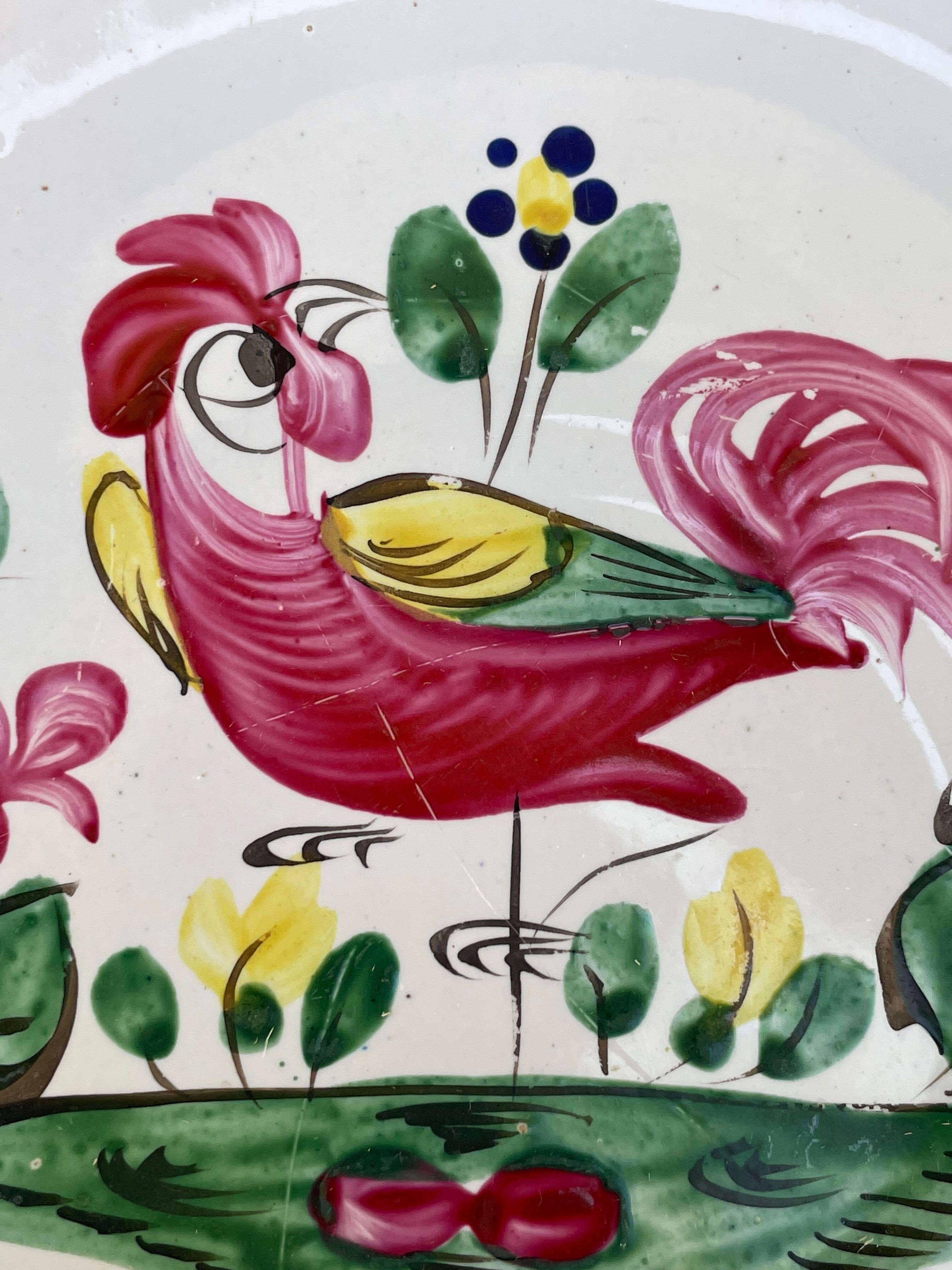 Antique plate with a flower and rooster pattern.