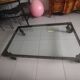 Industrial coffee table in solid metal with a glass top.
