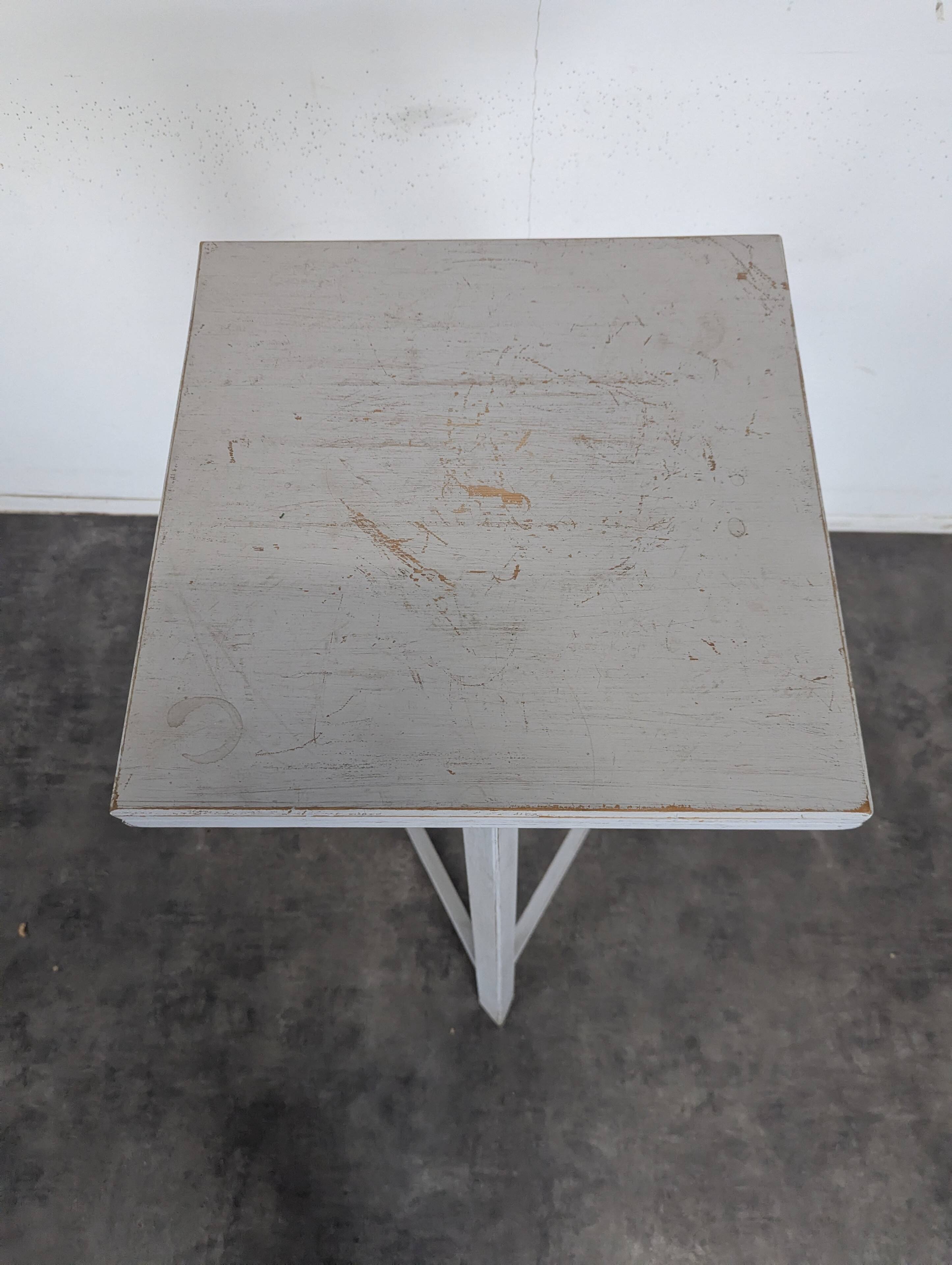 Tripod sculptor's stool in grey painted wood with a rotating top.
