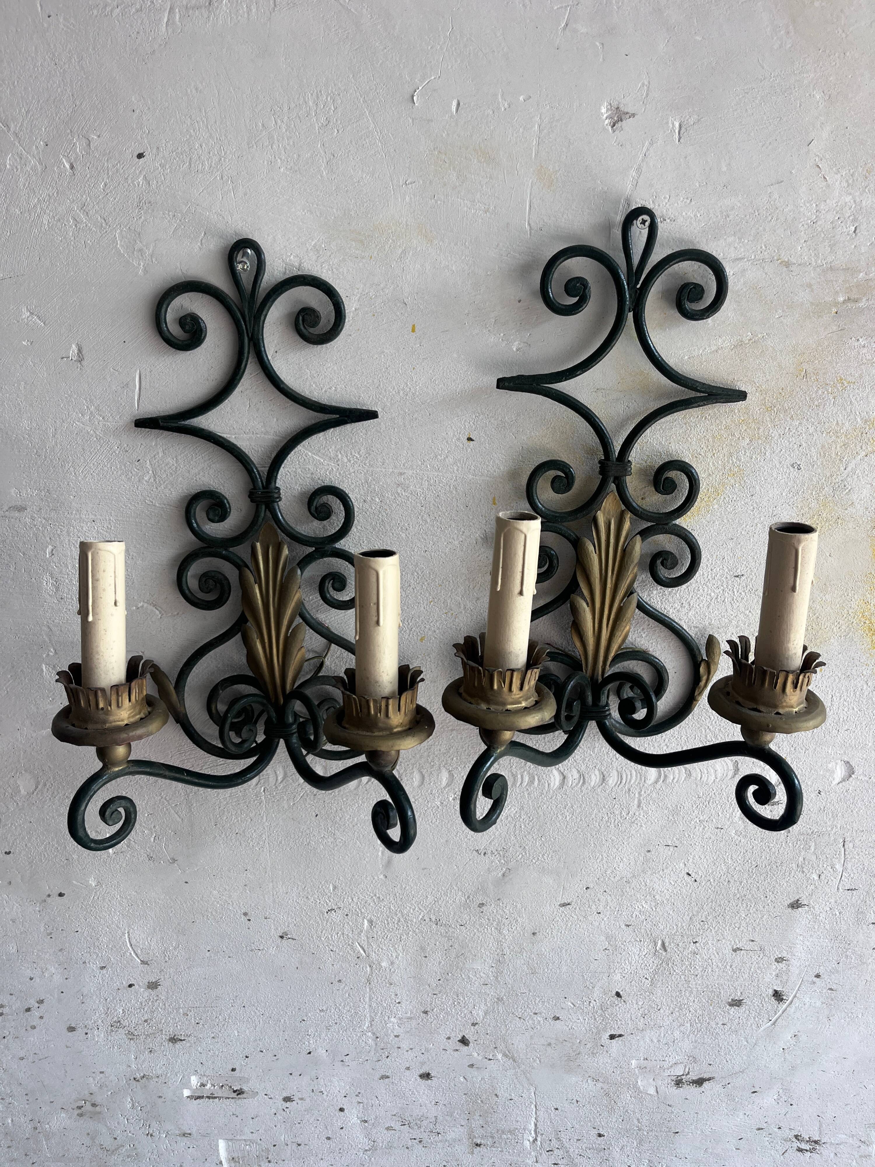 Pair of wall sconces in wrought iron with golden leaf patterns.