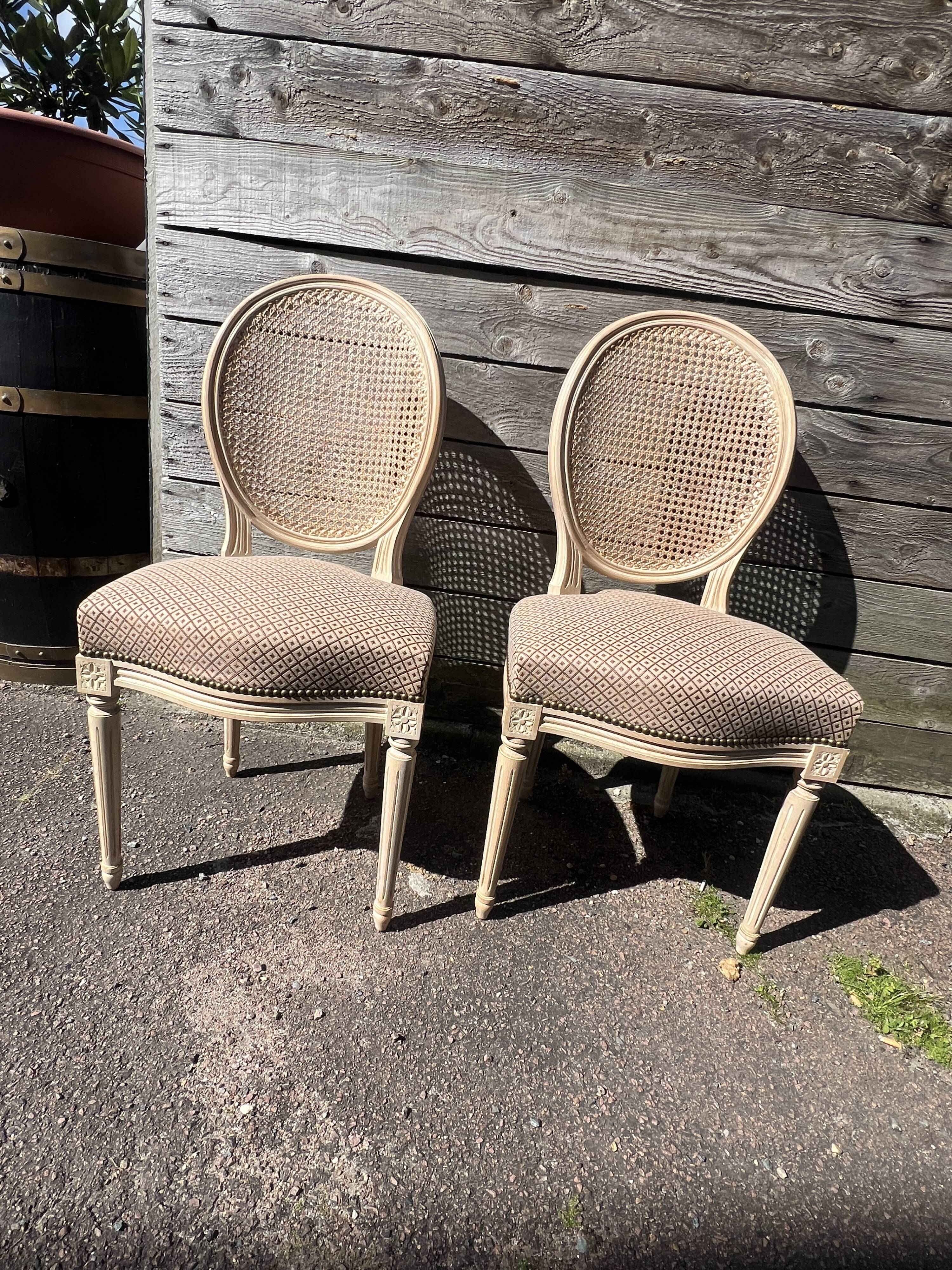 Pair of cerused chairs with fabric seats and caned backs.