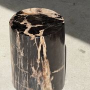 Black petrified wood side table with beige stripes and a semicircular shape.