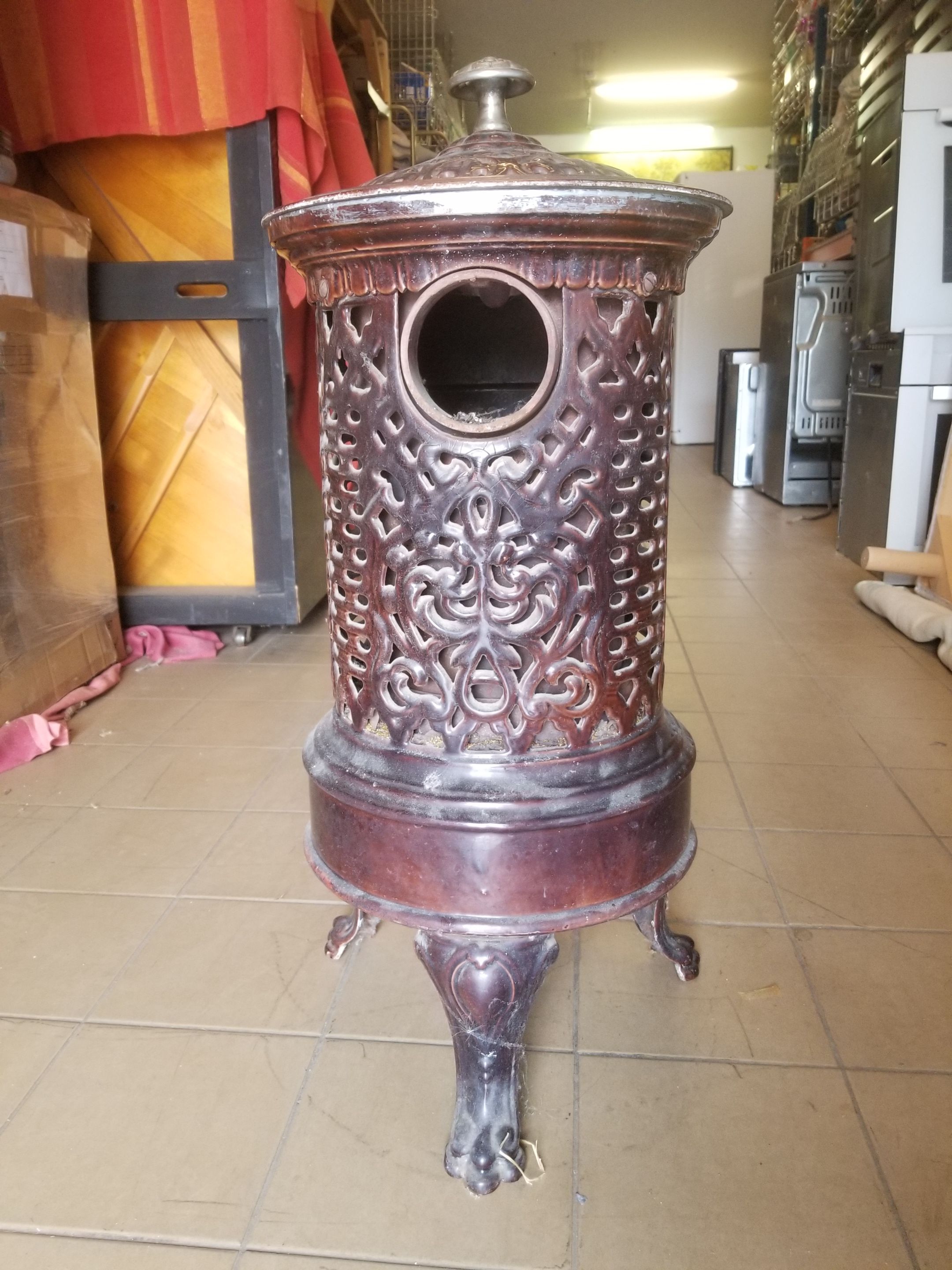 Old compact wood stove in enamelled cast iron with tripod feet with Lion's legs