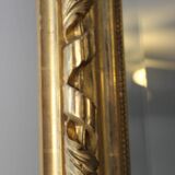Miroir ancien doré surmonté d'un fronton et glace biseautée