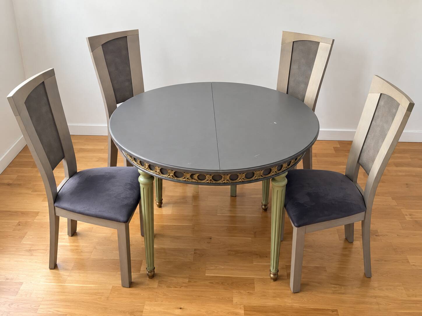 Extendable round table, 2 extensions, and 4 grey velvet chairs.