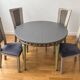 Extendable round table, 2 extensions, and 4 grey velvet chairs.