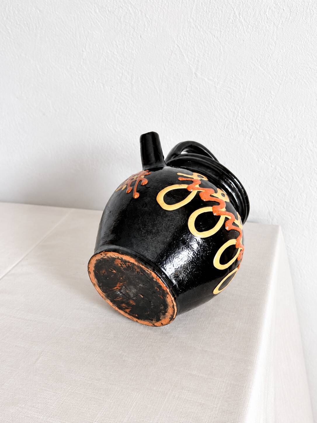 Old vase in glossy black ceramic, vintage exterior decoration.