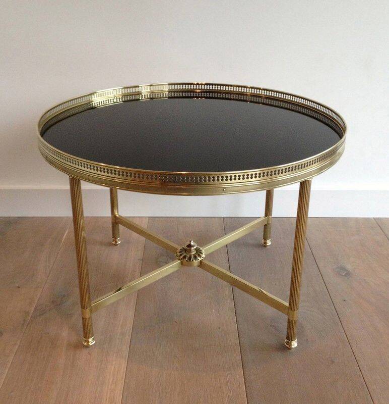 Round coffee table in brass with a black lacquered glass top by Maison Jansen.
