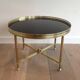 Round coffee table in brass with a black lacquered glass top by Maison Jansen.