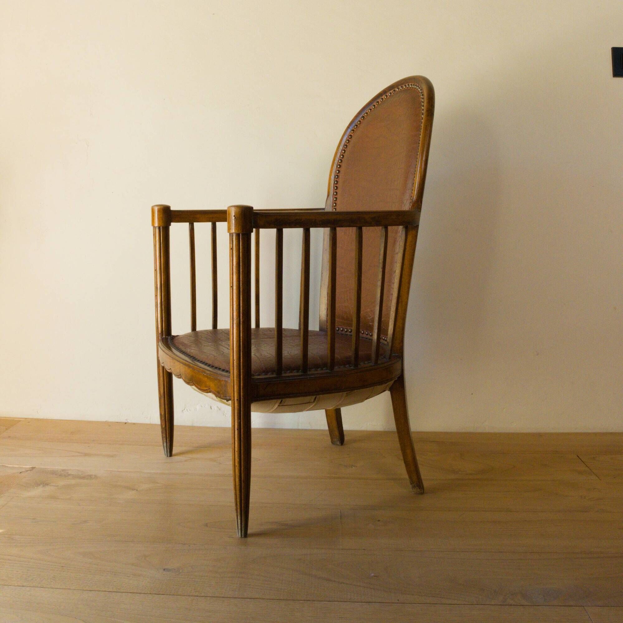 Antique armchair in solid wood and patinated brown leather, early 20th century.